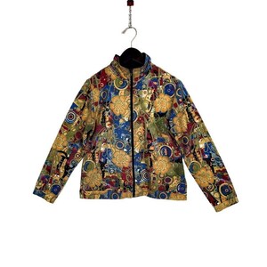 May include: A colorful zip-up jacket with a floral and geometric pattern in shades of gold, blue, red, and green. The jacket has a black collar and a full-length zipper. The jacket is hanging on a black hanger.