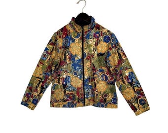 Könnte beinhalten: Bunte Jacke mit Reißverschluss und floralem und geometrischem Muster in Gold-, Blau-, Rot- und Grüntönen. Die Jacke hat einen schwarzen Kragen und einen durchgehenden Reißverschluss. Die Jacke hängt an einem schwarzen Kleiderbügel.