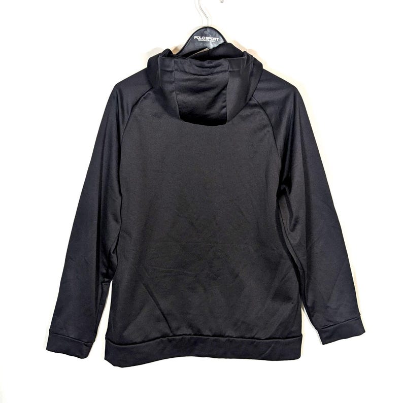 May include: A black hooded sweatshirt with a drawstring hood and long sleeves. The sweatshirt is hanging on a white background. The Polo Sport logo is visible on the hanger.