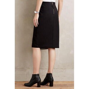 May include: A black pencil skirt with a back zipper and a slit. The skirt is paired with black ankle boots with a textured pattern and block heels. The outfit is suitable for business or casual wear.