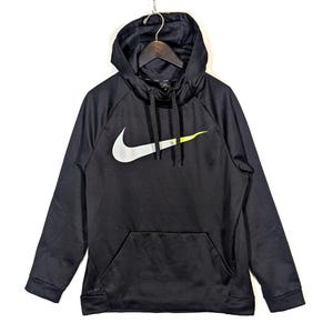 May include: Black Nike hoodie with a large white and neon green logo on the front. The hoodie has a drawstring hood, a front pocket, and long sleeves. The Nike logo is a prominent feature, adding a sporty aesthetic to the garment.