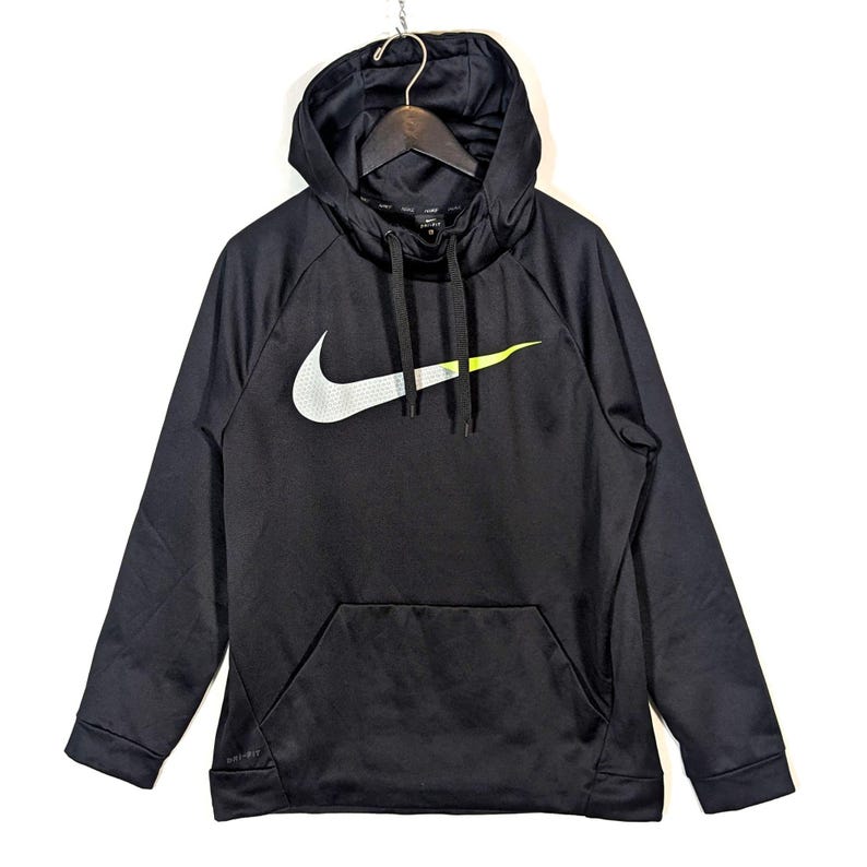 May include: Black Nike hoodie with a large white and neon green logo on the front. The hoodie has a drawstring hood, a front pocket, and long sleeves. The Nike logo is a prominent feature, adding a sporty aesthetic to the garment.