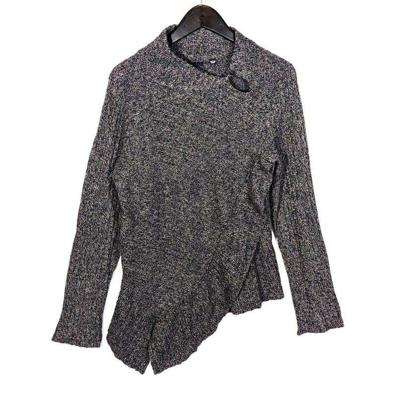 K&ouml;nnte beinhalten: Ein grau-schwarz melierter Pullover mit langen &Auml;rmeln und einem einzigartigen asymmetrischen Design. Der Pullover hat einen hohen Kragen und eine dekorative kreisf&ouml;rmige &Ouml;ffnung am Halsausschnitt. Der untere Saum hat einen ger&uuml;schten, geschichteten Effekt.