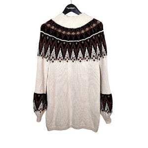 Puede incluir: Su&eacute;ter color crema con cuello alto y mangas largas. La parte superior del pecho y las mangas presentan un patr&oacute;n geom&eacute;trico en marr&oacute;n y blanco. El su&eacute;ter est&aacute; colgado de una percha negra.