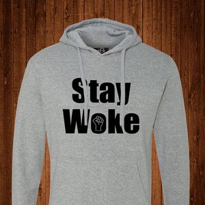 May include: A gray hooded sweatshirt with the text "stay woke" in black lettering and a raised fist symbol.