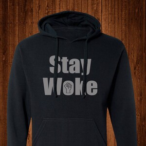 May include: A black hooded sweatshirt with the text "Stay Woke" in white letters and a raised fist symbol.
