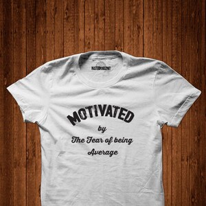 May include: White t-shirt with black text that reads "Motivated by The Fear of being Average".