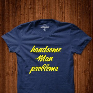 May include: A navy blue t-shirt with the text "handsome man problems" in yellow lettering.