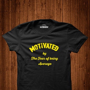May include: Black t-shirt with yellow text that reads "Motivated by The Fear of being Average".