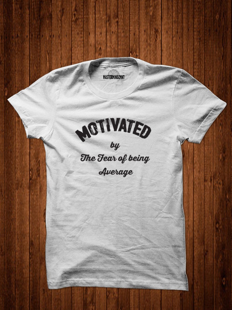 May include: White t-shirt with black text that reads "Motivated by The Fear of being Average".