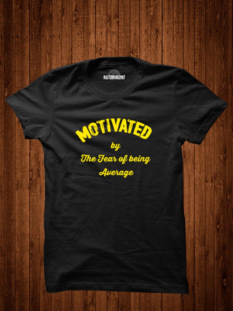 May include: Black t-shirt with yellow text that reads "Motivated by The Fear of being Average".