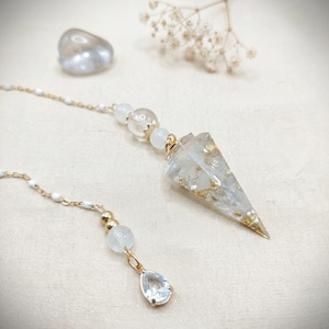 May include: A pendulum featuring a clear, cone-shaped resin point embedded with gold flakes, suspended from a gold-toned chain. The chain includes small white beads, clear round beads, and a small, clear, teardrop-shaped charm at the end.