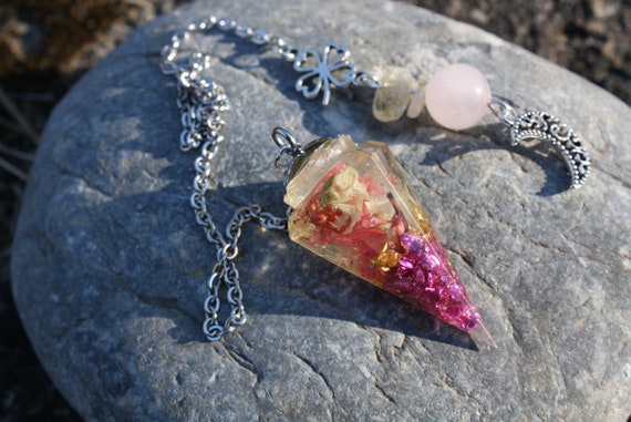 Divinatory pendulum dried flowers and crystal fragments