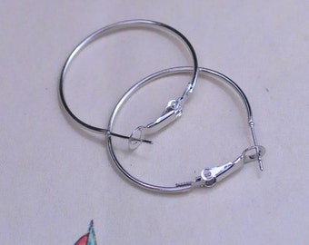 May include: A pair of silver hoop earrings with a hinged clasp.