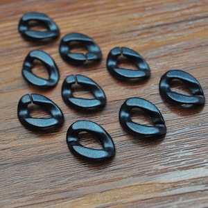 Puede incluir: Diez anillos de metal negro con forma ovalada redondeada. Los anillos tienen un acabado liso y brillante.
