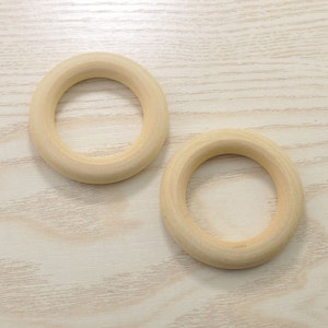 May include: Two unfinished wooden rings, perfect for crafting projects. The rings are smooth and have a natural wood color.