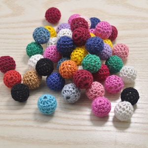 May include: A collection of colorful crocheted balls, featuring a variety of colors including red, blue, green, yellow, pink, and white. The balls are made of a soft, textured yarn and are perfect for crafting projects.