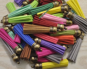 Puede incluir: Una colección de abalorios de borla de colores con tapas de metal dorado. Las borlas están hechas de material suave y peludo y vienen en una variedad de colores, incluyendo rojo, verde, azul, amarillo y marrón.