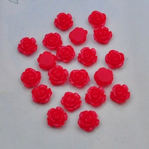 Peut inclure: Une collection de 20 embellissements en forme de rose en plastique rouge vif. Ces petites roses détaillées sont parfaites pour ajouter une touche d'élégance aux travaux manuels, aux bijoux et à d'autres projets.