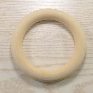 May include: A natural wood ring, smooth and unpainted, with a circular shape. The ring is approximately 6 inches in diameter.