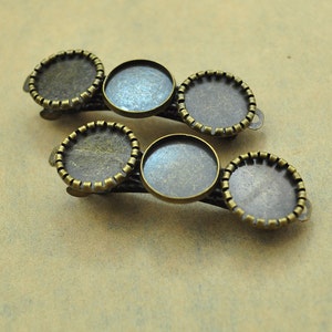 May include: A set of five antique gold-toned metal hair clips with round, bevelled glass inserts. The clips are designed to hold a variety of charms or embellishments.