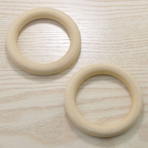 May include: Two unfinished wooden rings, each with a smooth, rounded surface. The rings are approximately 4 inches in diameter and are ideal for crafting projects.