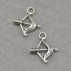 May include: Two silver-toned bow and arrow charms with a loop at the top for attaching to jewelry or other crafts.