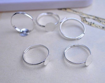 May include: Five silver adjustable ring blanks with round bezel settings. The bezels are smooth and ready for embellishment.