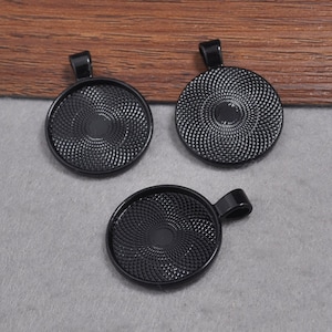 Puede incluir: Tres bandejas de colgantes de metal negro con una superficie texturizada y un bucle para colgar.