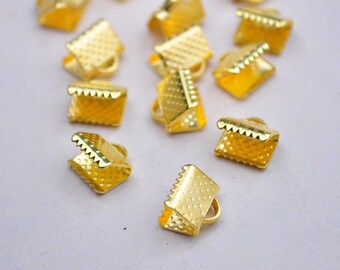 May include: A group of gold-colored metal clasps, each with a square shape and a textured surface. The clasps are designed for use in jewelry making or other craft projects.