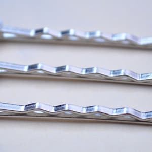 May include: Three silver hair clips with round, silver-toned metal embellishments at the top.