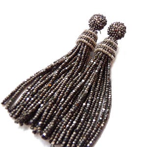 May include: A pair of long, black tassel earrings with silver accents. The tassels are made of small, round beads.