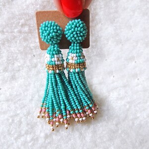 May include: A pair of turquoise beaded tassel earrings with gold accents and white and pink beads.