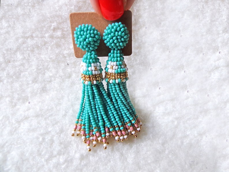May include: A pair of turquoise beaded tassel earrings with gold accents and white and pink beads.