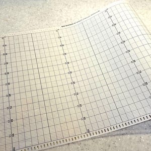 May include: A roll of graph paper with a grid pattern of black lines on a white background. The paper is marked with numbers from 10 to 100 along the vertical axis. Perforated edge on the bottom.