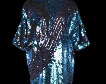 May include: A teal blue sequined dress with black and purple accents. The dress has a loose fit and a scoop neck.