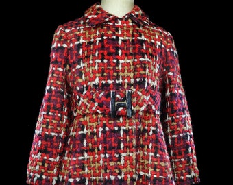 May include: A red, black, white, and brown tweed coat with a black belt and buckle. The coat has a collar and long sleeves.