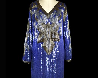 May include: A long-sleeved, sequined dress in a deep blue color with gold and silver accents. The dress has a V-neckline and a fitted silhouette.