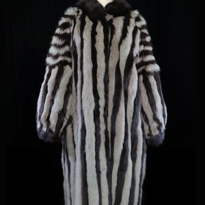 May include: A long, striped fur coat with a black and white pattern. The coat has a high collar and is made of a soft, luxurious fur.