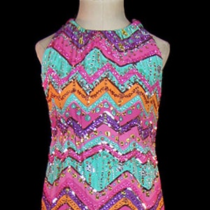 Puede incluir: Un vestido largo sin mangas con un patrón de chevron en tonos de rosa, naranja, morado y turquesa. El vestido está cubierto de lentejuelas y tiene un escote halter.