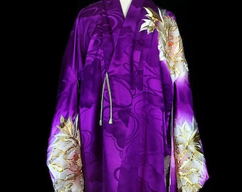 Könnte beinhalten: Ein lila Seidenkimono mit weißen und goldenen Blumenstickereien. Der Kimono hat ein traditionelles japanisches Design und ist ein wunderschönes Beispiel für traditionelle japanische Kleidung.