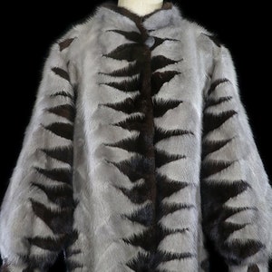 May include: A gray and brown fur jacket with a tiger stripe pattern. The jacket has a button closure and long sleeves.