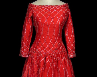 Puede incluir: Un vestido rojo con un patrón de diamantes y un corpiño ajustado. El vestido tiene mangas largas y una falda completa. El vestido está decorado con lentejuelas plateadas.