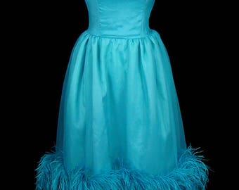 May include: A turquoise blue satin dress with a feather trim around the hem. The dress has a fitted bodice and a full skirt.