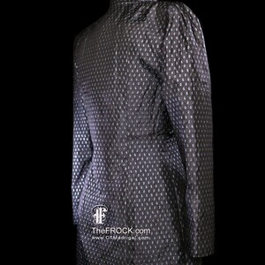 May include: A black and silver patterned dress with a high collar and long sleeves. The dress is on a mannequin and has a small logo on the bottom.