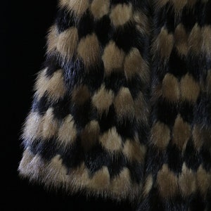 May include: Close-up of a black and brown fur fabric with a patterned design. The fur is soft and fluffy.