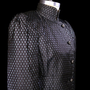 May include: A black and blue patterned dress with a high collar and button closures. The dress is on a mannequin.