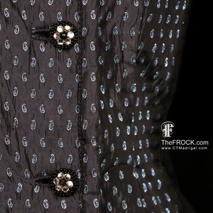May include: Black dress with a paisley pattern and two silver buttons. The dress has a fitted bodice and a full skirt.
