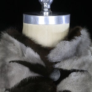 May include: A brown and gray fur coat with a large collar and a single button closure.