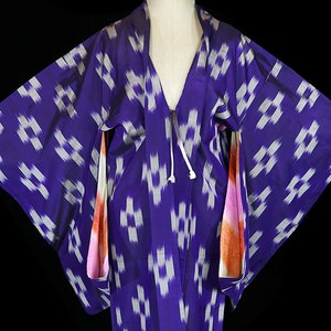May include: A purple and white patterned kimono with orange and pink accents on the sleeves. The kimono is made of silk and features a traditional Japanese design.